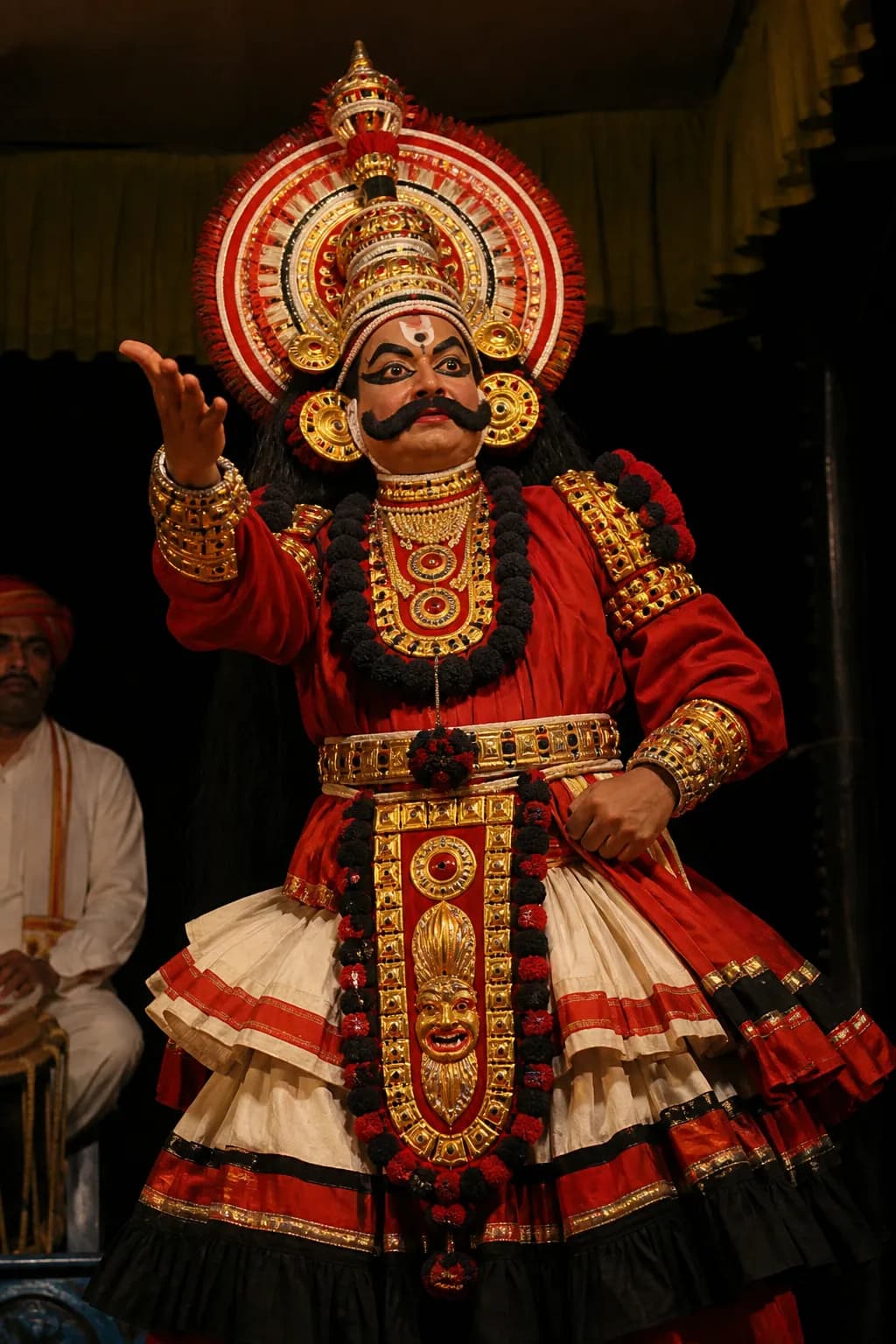 A Yakshagana performer in full costume and kirita headgear during a stage performance